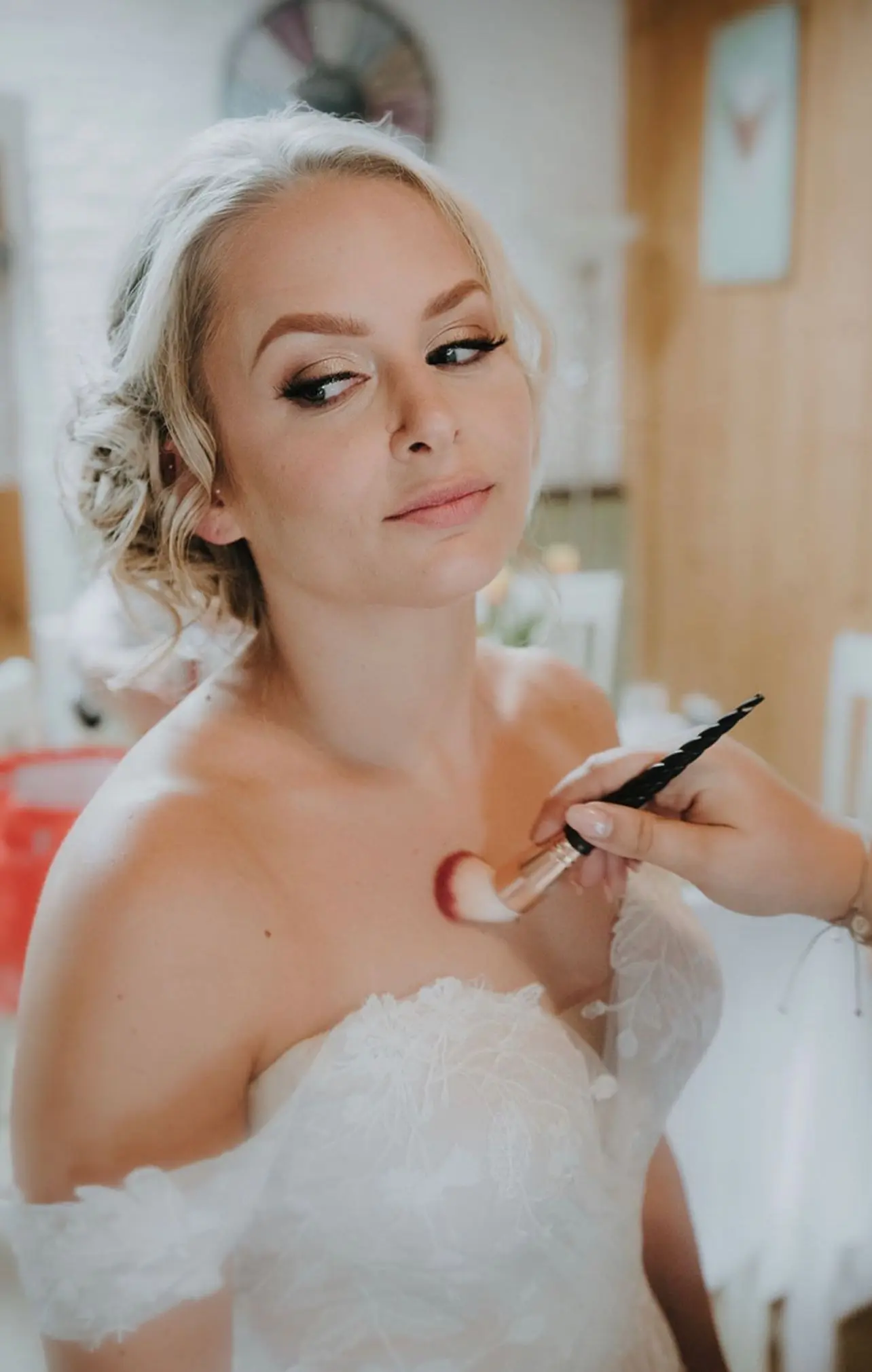 Bride in lace gown having lipstick applied